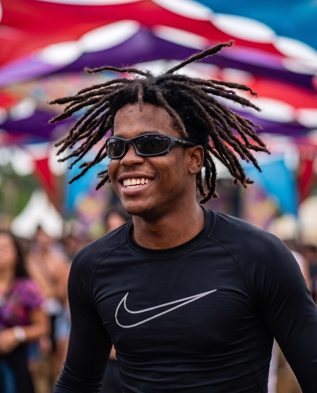 Rapaz sorrindo num festival, de óculos escuro